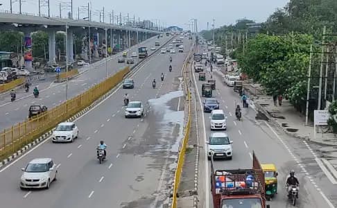Busy multi-lane corridor with elevated metro track and road traffic